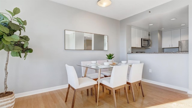 dining area featuring light wood-style floors and baseboards