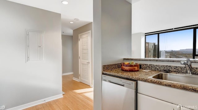 kitchen with electric panel, white cabinets, dishwashing machine, light wood-style flooring, and a sink