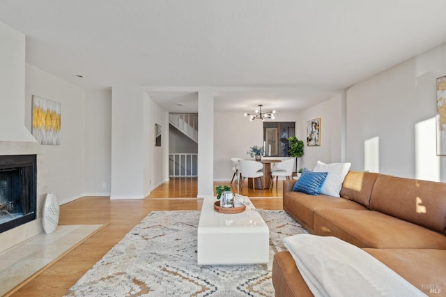 living room featuring an inviting chandelier, a fireplace, and light hardwood / wood-style flooring