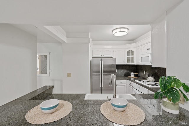 kitchen with kitchen peninsula, backsplash, white appliances, sink, and white cabinetry