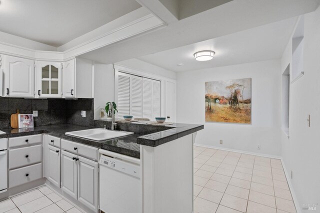 kitchen featuring kitchen peninsula, white dishwasher, sink, light tile patterned floors, and white cabinetry