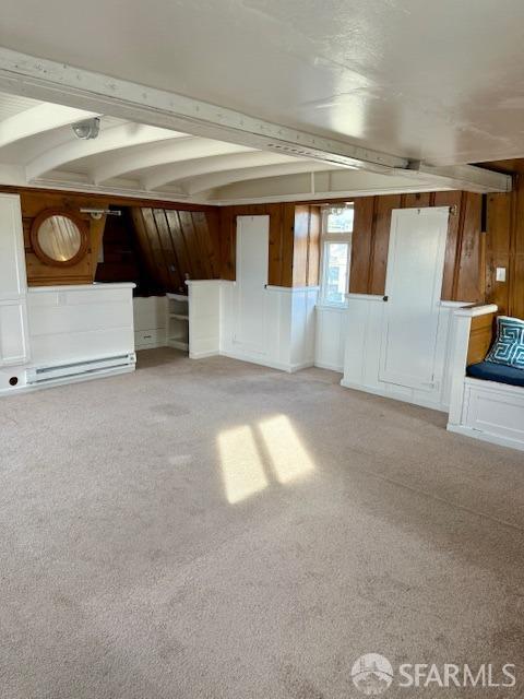 unfurnished living room with beam ceiling, carpet floors, and wooden walls