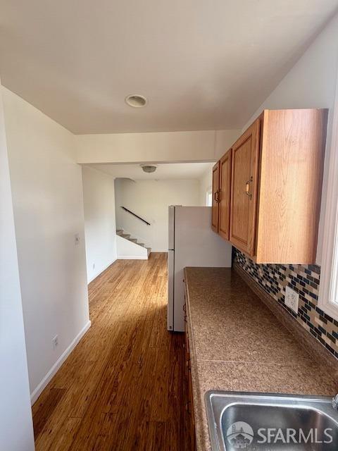 kitchen featuring white refrigerator, dark hardwood / wood-style flooring, sink, and decorative backsplash