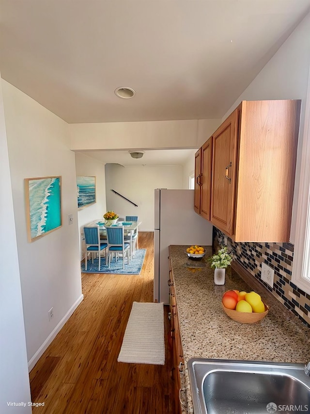 kitchen featuring dark hardwood / wood-style floors, tasteful backsplash, sink, dark stone counters, and white fridge