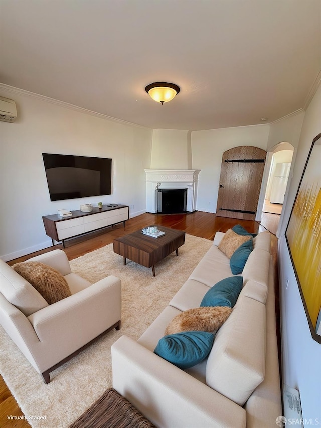 living room featuring hardwood / wood-style floors, crown molding, and a wall unit AC