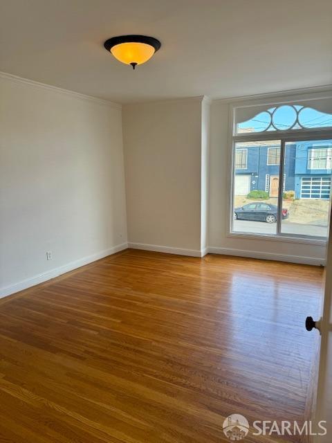 empty room with crown molding and hardwood / wood-style flooring