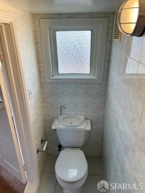 bathroom featuring tile walls, tile patterned floors, and toilet