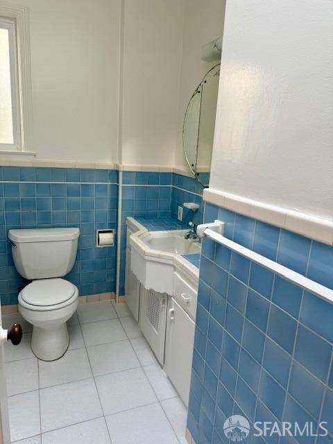 bathroom with tile patterned floors, toilet, vanity, and tile walls