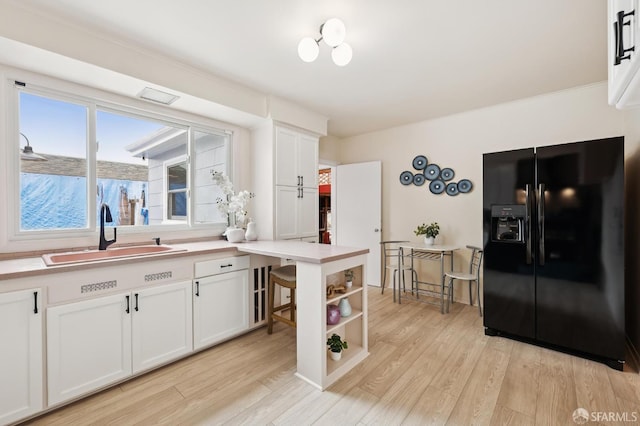 1285 Holloway Ave, San Francisco, CA 94132 - kitchen featuring black refrigerator with ice dispenser, white cabinetry, light wood-style flooring, light countertops, and open shelves