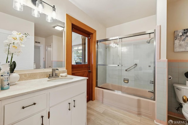 1285 Holloway Ave, San Francisco, CA 94132 - bathroom with vanity, bath / shower combo with glass door, wood finished floors, tile walls, and a wainscoted wall