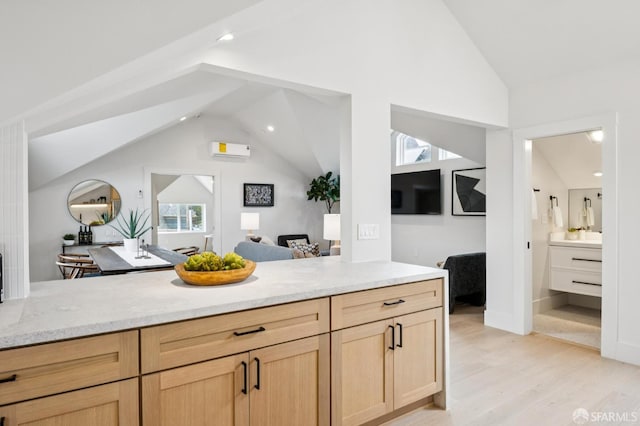 102 Baker St Unit A, San Francisco, CA 94117 - kitchen with vaulted ceiling, light brown cabinets, light stone counters, a wall mounted air conditioner, and open floor plan