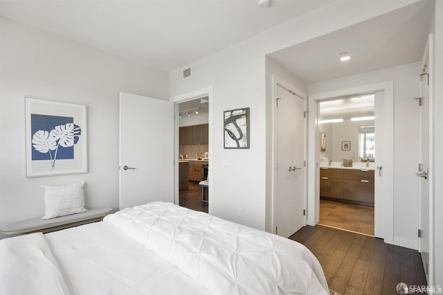 bedroom featuring dark wood-style floors, visible vents, and ensuite bathroom