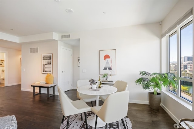 dining area with dark wood-style floors, visible vents, and baseboards