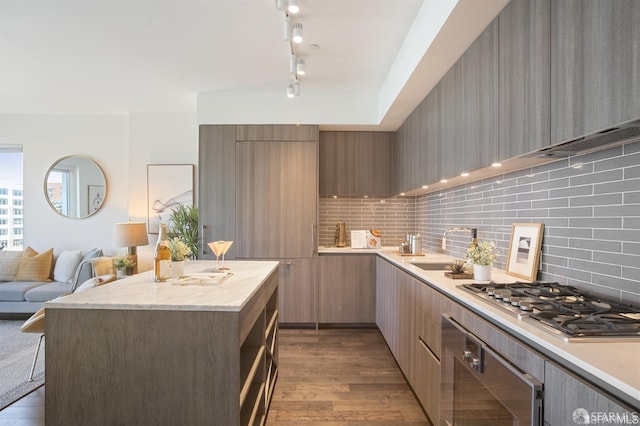 kitchen with stainless steel gas cooktop, light countertops, a sink, modern cabinets, and oven