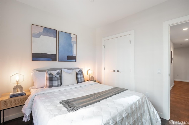 bedroom with a closet, recessed lighting, wood finished floors, and baseboards