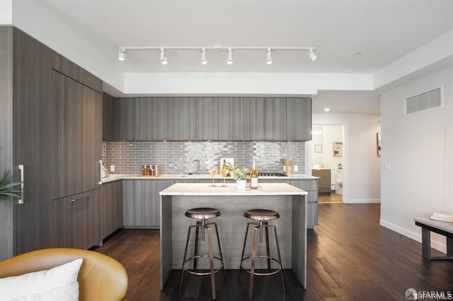 kitchen featuring light countertops, visible vents, a kitchen bar, and modern cabinets