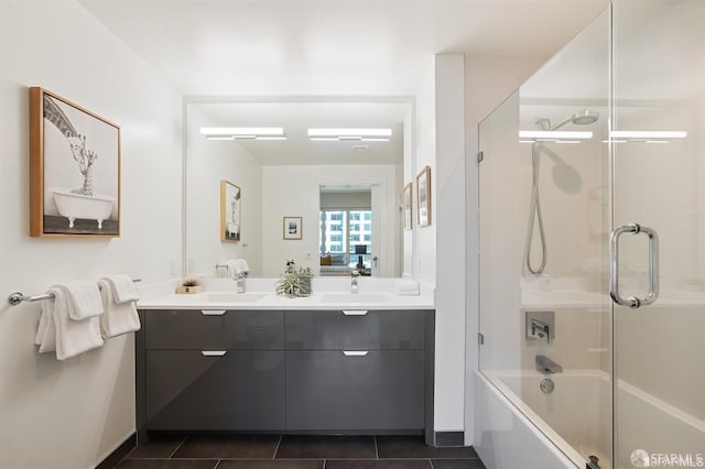 full bath featuring shower / bath combination with glass door, double vanity, a sink, and tile patterned floors