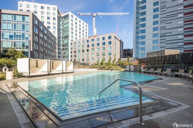 pool with a view of city, fence, and a patio