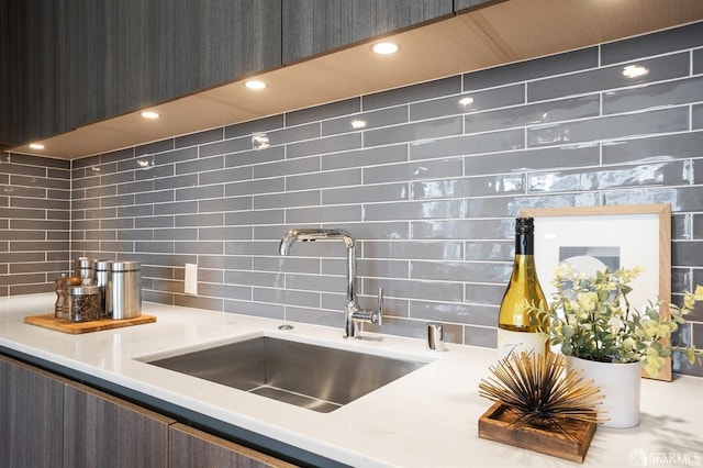 kitchen featuring light countertops, modern cabinets, a sink, and decorative backsplash