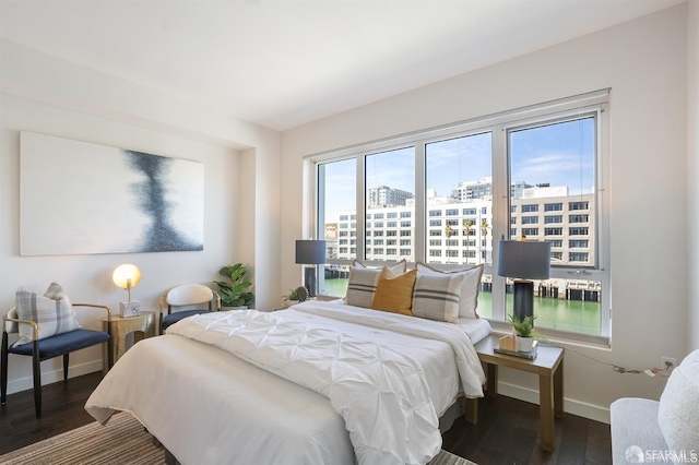 bedroom with baseboards, a city view, and wood finished floors