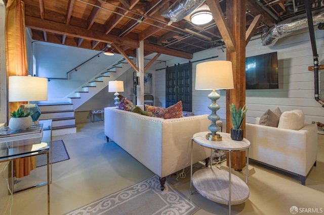 living room featuring wood walls, concrete flooring, and a barn door