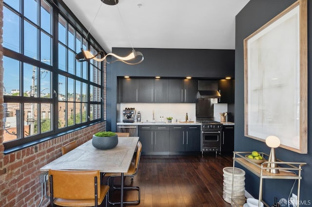 kitchen with brick wall, dark hardwood / wood-style floors, sink, stainless steel appliances, and wall chimney range hood