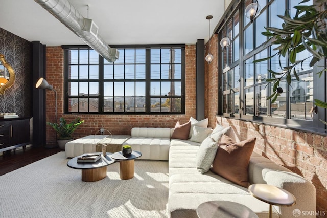 living room featuring hardwood / wood-style flooring, brick wall, and a wealth of natural light