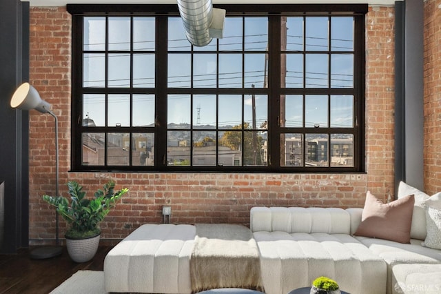 living room featuring a wealth of natural light, brick wall, and hardwood / wood-style floors