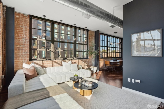 living room featuring a towering ceiling, brick wall, hardwood / wood-style floors, and a wall of windows