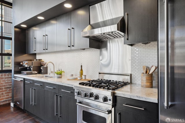 kitchen with appliances with stainless steel finishes, sink, decorative backsplash, and wall chimney range hood