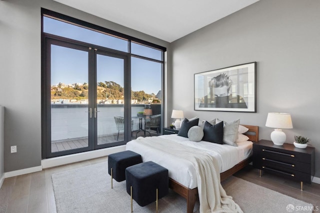 bedroom with wood-type flooring and a water view