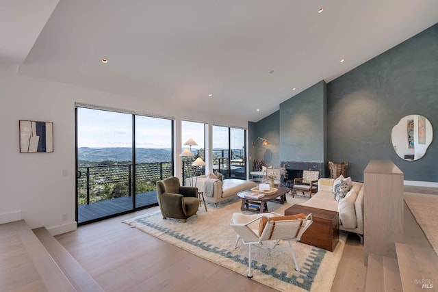 living room featuring recessed lighting, an accent wall, baseboards, and wood finished floors