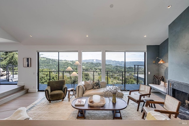 living room with recessed lighting, light wood finished floors, lofted ceiling, a premium fireplace, and a mountain view