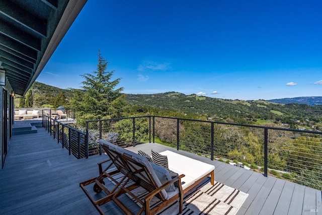 wooden terrace featuring a wooded view and a mountain view