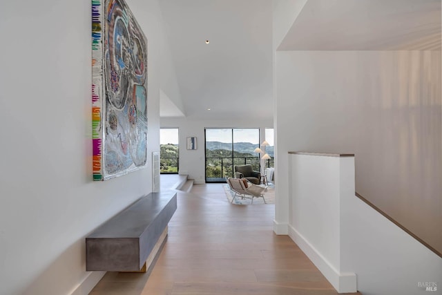 hallway featuring wood finished floors, baseboards, and an upstairs landing