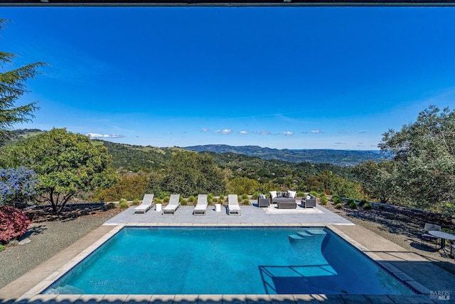 pool with a patio area, a mountain view, and an outdoor living space