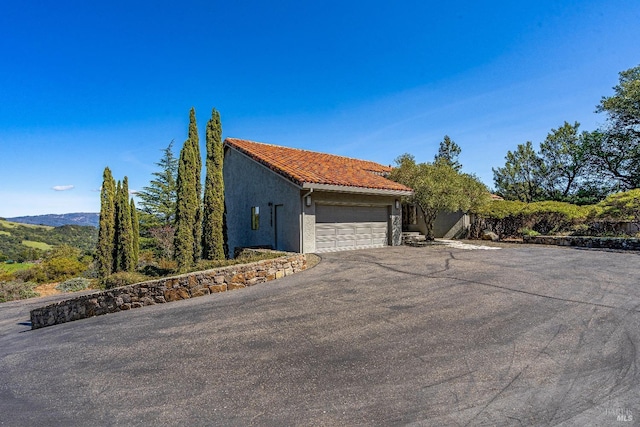 view of side of property featuring driveway, stucco siding, and a tile roof