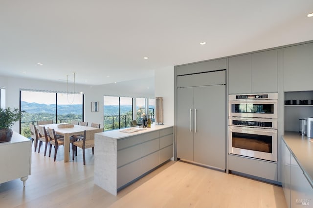 kitchen featuring paneled refrigerator, gray cabinetry, modern cabinets, and double oven