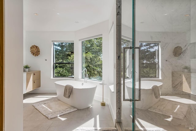 full bathroom with a freestanding tub, baseboards, a marble finish shower, and tile patterned flooring