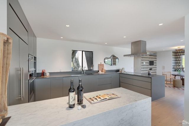 kitchen with a sink, gray cabinets, island exhaust hood, and modern cabinets