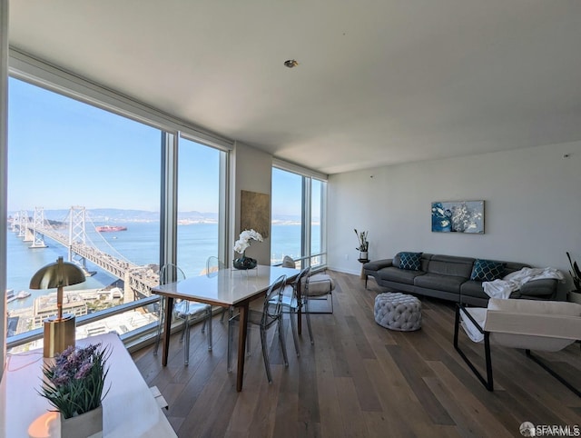 dining area featuring floor to ceiling windows, a water view, and wood finished floors