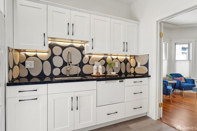 kitchen view of a sink, white cabinets, tasteful backsplash, and dishwasher