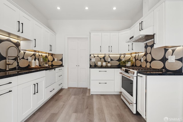 kitchen with white range with gas cooktop, under cabinet range hood, decorative backsplash, dark countertops, and recessed lighting