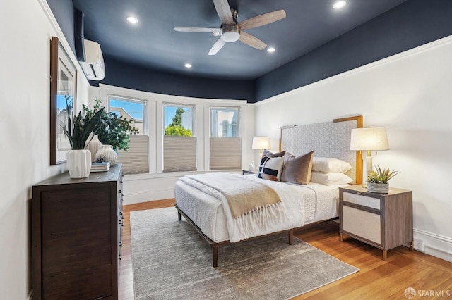 bedroom featuring an AC wall unit, wood finished floors, recessed lighting, baseboards, and ceiling fan