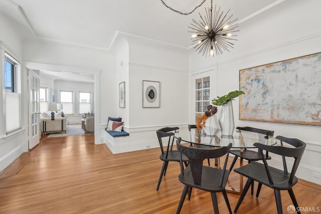 dining area with a chandelier, light wood finished floors, and a decorative wall