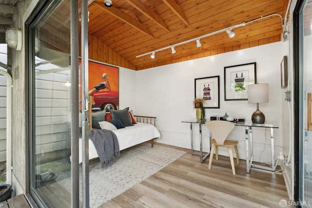 bedroom with rail lighting, wood ceiling, wood finished floors, and baseboards