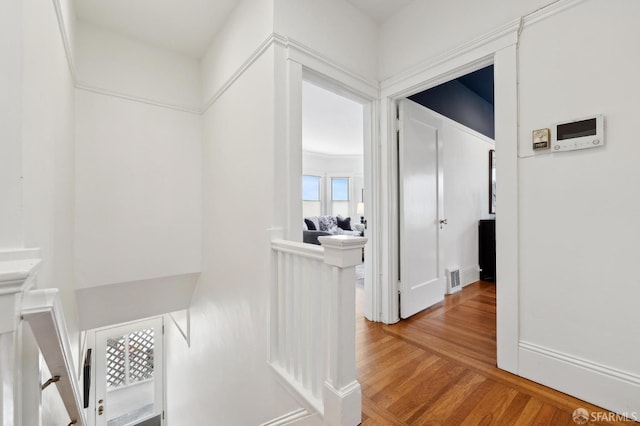 hall with light wood-type flooring and an upstairs landing