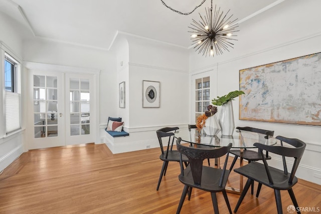 dining area with french doors, a chandelier, a decorative wall, healthy amount of natural light, and wood finished floors