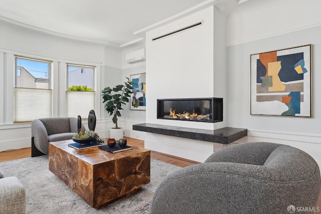 living room featuring wood finished floors, a glass covered fireplace, and a wall mounted AC