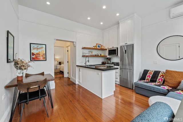 719-721 Shotwell St, San Francisco, CA 94110 - kitchen with stainless steel appliances, dark countertops, an AC wall unit, white cabinetry, and a peninsula